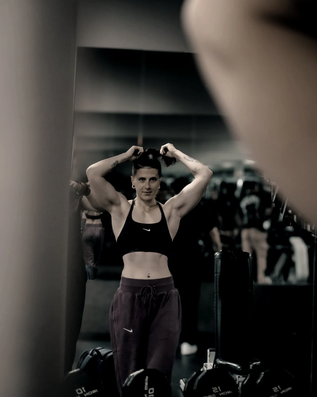 A woman tying her hair up in the gym mirror
